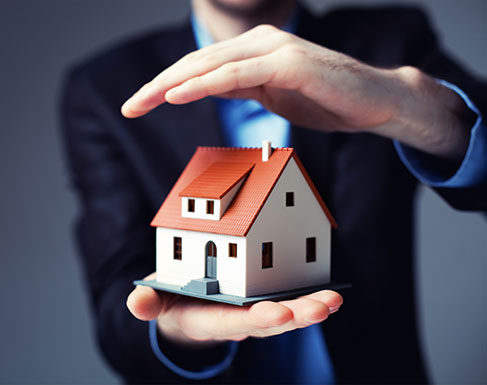 Man holding a house model in his hands and protecting it